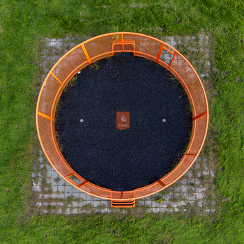 Aerial view of an orange circular structure enclosing dark gravel contrasting with the surrounding green grass and tiled pathway Radiopad Flevoland Netherlands.