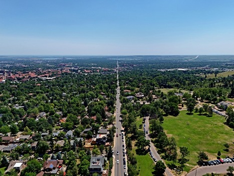 Aerial view of Chautauqua Park in Boulder Colorado with lush green trees a straight road with cars and residential neighborhoods under a clear blue sky. Boulder Colorado United States. Aerial view of Chautauqua Park in Boulder Colorado with lush green trees a straight road with cars and residential neighborhoods under a clear blue sky. Boulder Colorado United States.