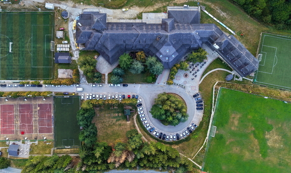 Aerial view of Brzece Sports Centar featuring multiple soccer fields tennis courts a large central building with a dark roof and surrounding parking areas in Brzece Rasina District Serbia.