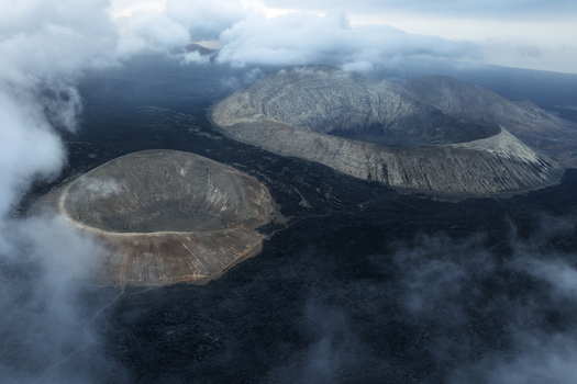 Aerial view of volcanic craters surrounded by dark lava fields and white clouds in Lanzarote Canarias Spain. Aerial view of volcanic craters surrounded by dark lava fields and white clouds in Lanzarote Canarias Spain.