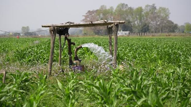 View of a water pump irrigating a green field Nepal.