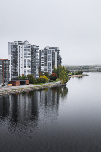 View of modern apartment buildings along the waterfront of a calm lake with autumn foliage under a cloudy sky in Jyvaskyla Central Finland Finland.