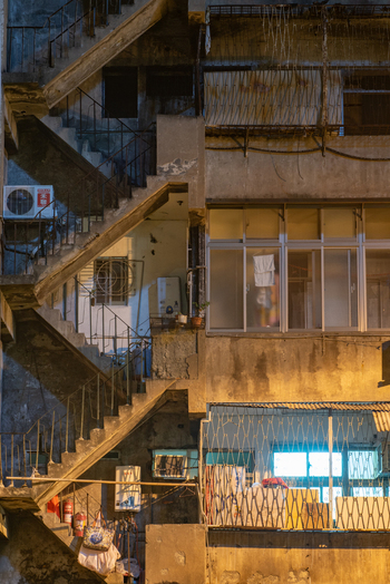 View of a weathered residential building with an external concrete staircase metal security grilles air conditioning units and laundry on balconies in Guangfu Village Taipei City Taiwan. View of a weathered residential building with an external concrete staircase metal security grilles air conditioning units and laundry on balconies in Guangfu Village Taipei City Taiwan.