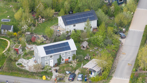 Aerial view of sustainable wooden houses with solar panels on rooftops and lush green gardens in Ecodorp Bolderburen Almere Flevoland Netherlands. Aerial view of sustainable wooden houses with solar panels on rooftops and lush green gardens in Ecodorp Bolderburen Almere Flevoland Netherlands.