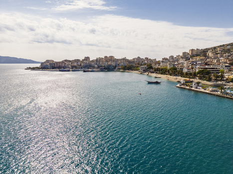 Aerial view of Saranda coastline with turquoise Ionian Sea waters sandy beaches and urban buildings nestled along the shore in Saranda Vlore County Albania. Aerial view of Saranda coastline with turquoise Ionian Sea waters sandy beaches and urban buildings nestled along the shore in Saranda Vlore County Albania.
