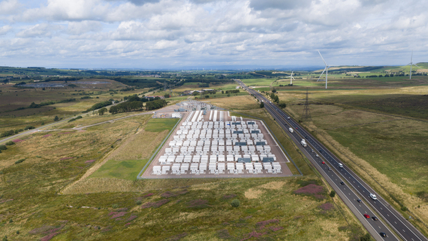 Aerial view of a large scale battery energy storage system facility with rows of white containers situated in a rural landscape next to a highway in Coalburn Scotland United Kingdom.