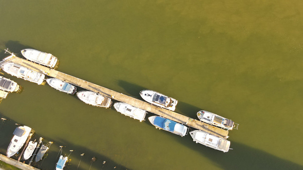 Aerial view of various motorboats and yachts moored along a wooden pier in the river in Chartrettes Ile de France France. Aerial view of various motorboats and yachts moored along a wooden pier in the river in Chartrettes Ile de France France.