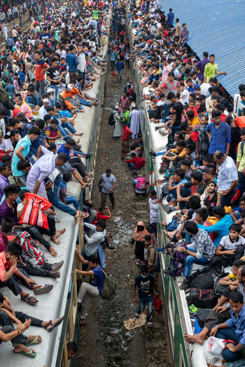 Dhaka Bangladesh 15 June 2018 View of the Airport Railway Station with a massive crowd of people sitting on the roofs of two trains and climbing the sides. Dhaka Bangladesh 15 June 2018 View of the Airport Railway Station with a massive crowd of people sitting on the roofs of two trains and climbing the sides.