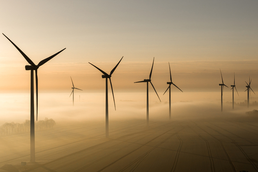 Aerial view of wind turbines rise majestically through the ethereal fog their silhouettes stark against the soft muted tones of the morning sky Wislina Pomeranian Voivodeship Poland. Aerial view of wind turbines rise majestically through the ethereal fog their silhouettes stark against the soft muted tones of the morning sky Wislina Pomeranian Voivodeship Poland.