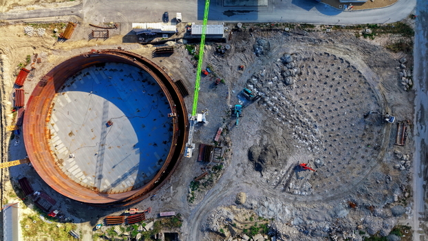 Aerial view of the assembly of a large industrial fuel tank at a refinery construction site with a crane and foundation work in Kovin Vojvodina Serbia. Aerial view of the assembly of a large industrial fuel tank at a refinery construction site with a crane and foundation work in Kovin Vojvodina Serbia.