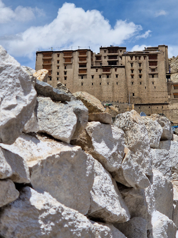 View of Leh Palace a historic royal palace overlooking the town with large white rocks in the foreground under a blue sky with clouds in Leh Ladakh India.