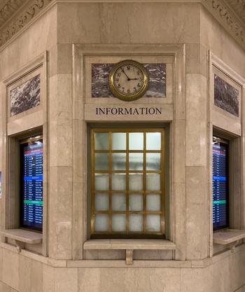 View of the iconic information booth with its brass clock and digital departure screens inside Grand Central Terminal in New York New York United States. View of the iconic information booth with its brass clock and digital departure screens inside Grand Central Terminal in New York New York United States.