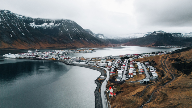 Aerial view of stark contrasts where dark waters meet the rugged coastline nestled beneath snow dusted mountains Ísafjörður Iceland. Aerial view of stark contrasts where dark waters meet the rugged coastline nestled beneath snow dusted mountains Ísafjörður Iceland.