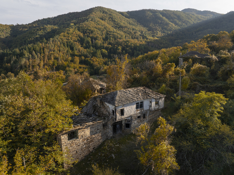 Aerial view of an abandoned stone house with a slate roof nestled among dense autumn forests in the mountains of Dyadovtsi Kardzhali Province Bulgaria. Aerial view of an abandoned stone house with a slate roof nestled among dense autumn forests in the mountains of Dyadovtsi Kardzhali Province Bulgaria.