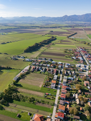 Aerial view of a village with red roofs surrounded by green and brown fields and distant mountains Bela Dulice Zilina Region Slovakia. Aerial view of a village with red roofs surrounded by green and brown fields and distant mountains Bela Dulice Zilina Region Slovakia.