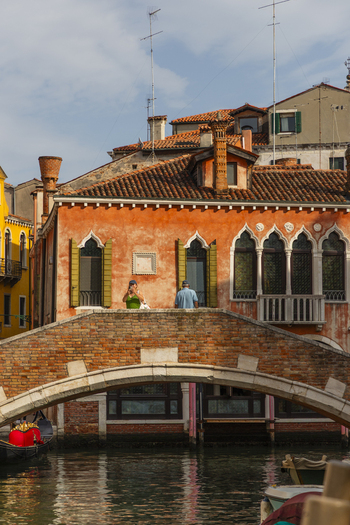 Venice Italy 21 September 2026 View of a historic brick bridge over a canal in Venice featuring orange Venetian architecture with arched windows and green shutters. Venice Italy 21 September 2026 View of a historic brick bridge over a canal in Venice featuring orange Venetian architecture with arched windows and green shutters.