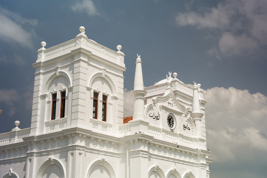 View of the historic white facade and clock tower of the Meeran Jumma Mosque under a cloudy sky in Galle Southern Province Sri Lanka.