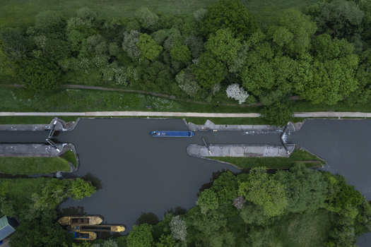 Aerial view of Hatton Locks on the Grand Union Canal with a narrowboat navigating the lock system surrounded by lush green trees and vegetation in Hatton England United Kingdom. Aerial view of Hatton Locks on the Grand Union Canal with a narrowboat navigating the lock system surrounded by lush green trees and vegetation in Hatton England United Kingdom.