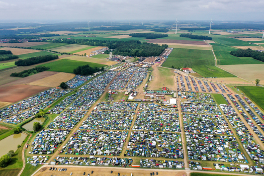 Herzogenaurach Germany 26 July 2025 Aerial view of Open Beatz Festival campsite with thousands of tents and cars spread across green fields under a cloudy sky.