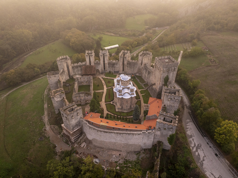 Aerial view of Manasija Monastery a fortified medieval Serbian Orthodox monastery with high stone walls and towers surrounded by lush green hills in Despotovac Pomoravski okrug Serbia.