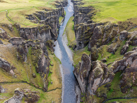 Aerial view of the deep Fjadrargljufur canyon with a river flowing through steep moss covered rock formations in Iceland. Aerial view of the deep Fjadrargljufur canyon with a river flowing through steep moss covered rock formations in Iceland.