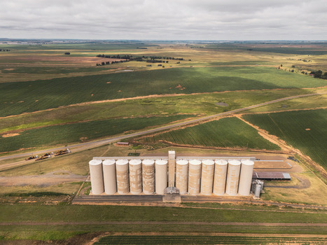 Aerial view of large grain silos standing amidst vast agricultural fields and rural roads under a cloudy sky Thabo Mofutsanyana District Municipality Free State South Africa. Aerial view of large grain silos standing amidst vast agricultural fields and rural roads under a cloudy sky Thabo Mofutsanyana District Municipality Free State South Africa.