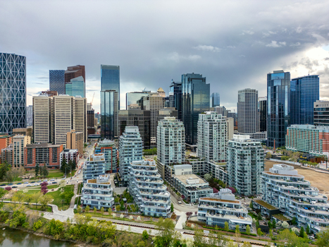 Aerial view of the Calgary skyline featuring modern skyscrapers residential buildings and the Bow River under a cloudy sky in Calgary Alberta Canada.