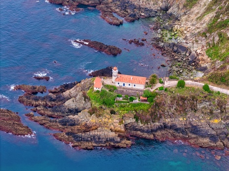 Aerial view of the historic lighthouse perched on a rocky cliff surrounded by the blue waters of the Cantabrian Sea in Cudillero Asturias Spain. Aerial view of the historic lighthouse perched on a rocky cliff surrounded by the blue waters of the Cantabrian Sea in Cudillero Asturias Spain.