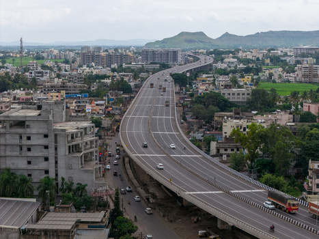 Aerial view of a modern elevated highway winding through the urban landscape with surrounding greenery and distant hills in Karad Maharashtra India.