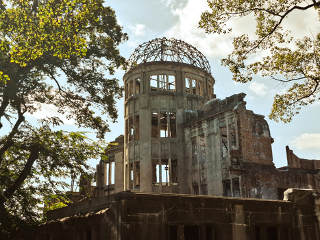 View of the historic Hiroshima Peace Memorial with its iconic exposed steel dome frame and weathered brick walls surrounded by lush green trees in Hiroshima Hiroshima Japan. View of the historic Hiroshima Peace Memorial with its iconic exposed steel dome frame and weathered brick walls surrounded by lush green trees in Hiroshima Hiroshima Japan.