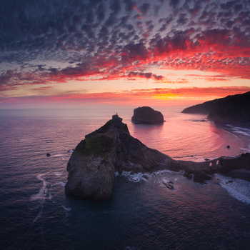 Aerial view of Gaztelugatxe islet and its stone bridge under a vibrant sunset sky Gaztelugatxeko Doniene Basque Country Spain. Aerial view of Gaztelugatxe islet and its stone bridge under a vibrant sunset sky Gaztelugatxeko Doniene Basque Country Spain.