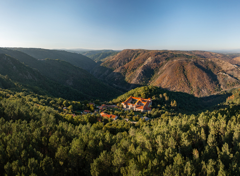 Aerial view of the Monastery of Santo Estevo de Ribas de Sil nestled within the lush green forests and rolling hills of the Ribeira Sacra region in O Covelo Ourense Spain.