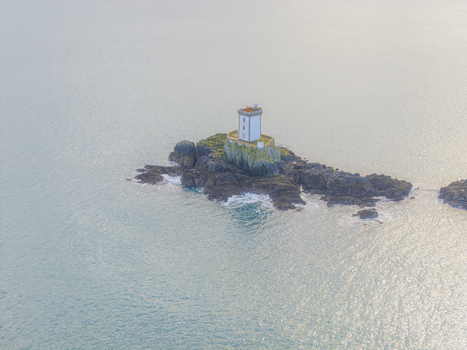 Aerial view of Phare de L Ost Pic lighthouse on a rocky islet surrounded by calm turquoise sea water under soft daylight Plouezec France. Aerial view of Phare de L Ost Pic lighthouse on a rocky islet surrounded by calm turquoise sea water under soft daylight Plouezec France.