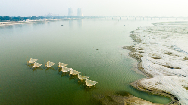 Aerial view of traditional fishing nets set in the Padma River with the Hardinge Bridge and power plant cooling towers in the distance in Pabna Rajshahi Division Bangladesh.