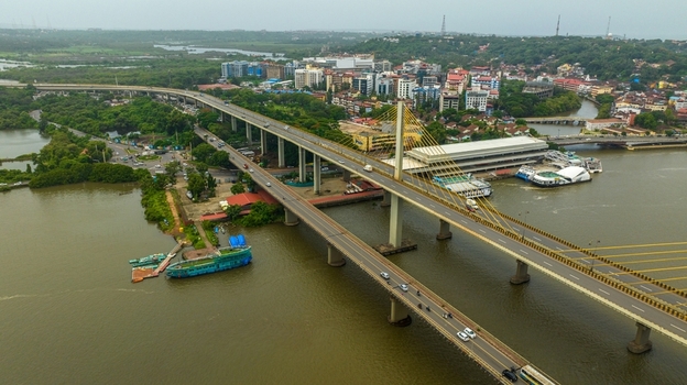Aerial view of the Atal Setu bridge spanning the Mandovi River with the city skyline of Panaji in the background surrounded by lush greenery and boats in Panaji Goa India.