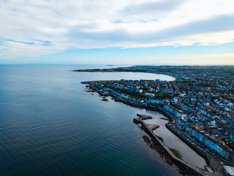 Aerial view of Bangor Harbour and Town with colorful buildings along the coastline stone piers and calm sea under a cloudy sky in Bangor Northern Ireland United Kingdom.