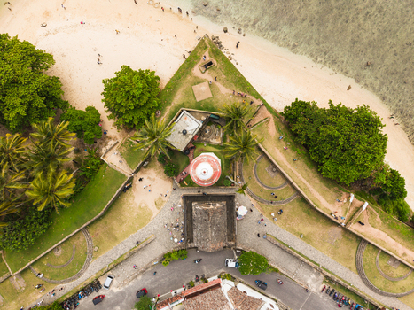Aerial view of the historic Galle Lighthouse and stone fortifications of Galle Fort surrounded by palm trees and a sandy beach in Galle Southern Province Sri Lanka. Aerial view of the historic Galle Lighthouse and stone fortifications of Galle Fort surrounded by palm trees and a sandy beach in Galle Southern Province Sri Lanka.