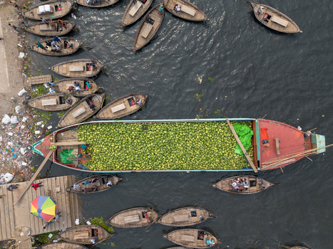 Dhaka Bangladesh 04 April 2026 Aerial view of boats one laden with green produce clustered by a riverbank casting reflections on the water s surface. Dhaka Bangladesh 04 April 2026 Aerial view of boats one laden with green produce clustered by a riverbank casting reflections on the water s surface.