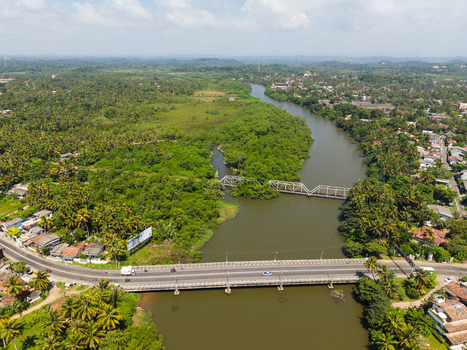 Aerial view of the Gin Ganga river winding through lush tropical vegetation with road and rail bridges Galle Southern Province Sri Lanka.