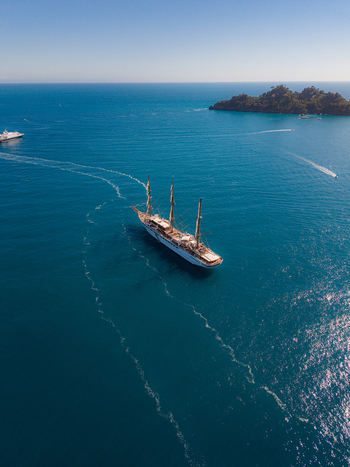 Aerial view of a large three masted sailing ship cruising on the turquoise Mediterranean Sea near the rocky coastline Portofino Liguria Italy. Aerial view of a large three masted sailing ship cruising on the turquoise Mediterranean Sea near the rocky coastline Portofino Liguria Italy.