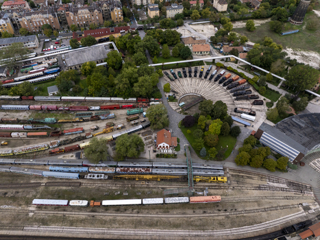 Aerial view of the Hungarian Railway Museum featuring the historic roundhouse with vintage locomotives arranged on tracks surrounded by lush trees and railway infrastructure in Budapest Hungary. Aerial view of the Hungarian Railway Museum featuring the historic roundhouse with vintage locomotives arranged on tracks surrounded by lush trees and railway infrastructure in Budapest Hungary.