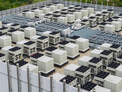 Aerial view of a data center rooftop featuring rows of industrial HVAC cooling units and ventilation fans United Kingdom.