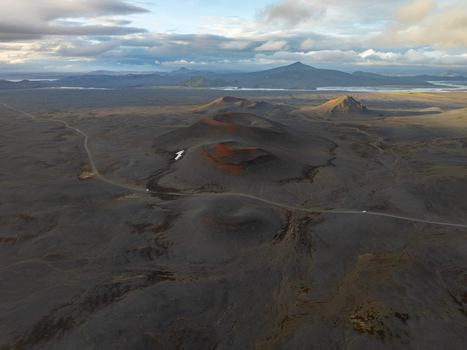 Aerial view of Landmannalaugar volcanic craters and rugged landscape with a winding road under a dramatic cloudy sky in Rangarthing ytra Iceland. Aerial view of Landmannalaugar volcanic craters and rugged landscape with a winding road under a dramatic cloudy sky in Rangarthing ytra Iceland.