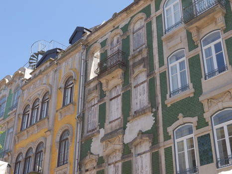 View of historic buildings with colorful tiled facades arched windows and wrought iron balconies under a clear blue sky in Porto Porto District Portugal. View of historic buildings with colorful tiled facades arched windows and wrought iron balconies under a clear blue sky in Porto Porto District Portugal.