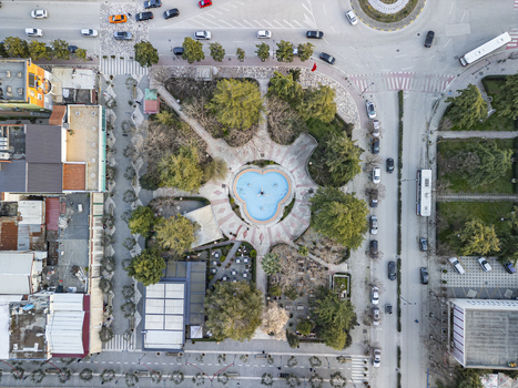 Aerial view of the Square of Independence with its distinctive clover shaped fountain surrounded by trees paved walkways and urban buildings in Fier Qarku i Fierit Albania.