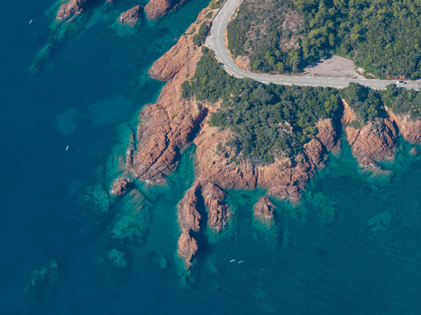 Aerial view of the red rock cliffs of Le Trayas meeting the turquoise Mediterranean Sea with a coastal road winding along rugged coastline in Saint Raphael Provence Alpes Cote d Azur France. Aerial view of the red rock cliffs of Le Trayas meeting the turquoise Mediterranean Sea with a coastal road winding along rugged coastline in Saint Raphael Provence Alpes Cote d Azur France.