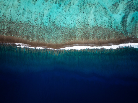 Aerial view of the vibrant coral reef and deep blue ocean waters with white surf breaking along the reef edge in Moorea Maiao Windward Islands French Polynesia. Aerial view of the vibrant coral reef and deep blue ocean waters with white surf breaking along the reef edge in Moorea Maiao Windward Islands French Polynesia.