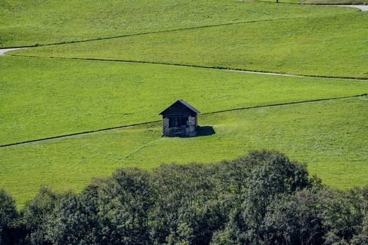 View of a small rustic stone hut standing in the middle of lush green alpine meadows near the Sankt Gotthard Pass in Airolo Ticino Switzerland.