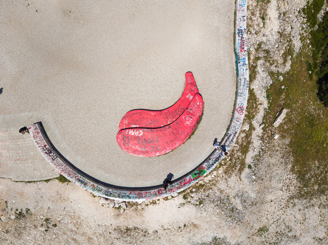Aerial view of the Panorama Llogora viewpoint featuring red lip shaped benches and graffiti covered walls on a rocky mountain pass in Himare Qarku i Vlores Albania.