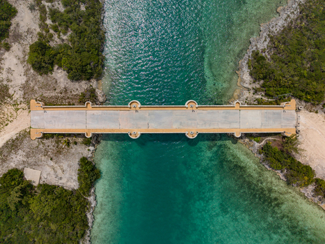 Aerial view of Crab Cay Bridge with semi circular lookouts crossing a turquoise water channel surrounded by lush tropical vegetation in Exuma Exuma The Bahamas. Aerial view of Crab Cay Bridge with semi circular lookouts crossing a turquoise water channel surrounded by lush tropical vegetation in Exuma Exuma The Bahamas.